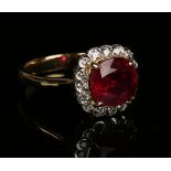 An 18ct gold, treated ruby and diamond cluster ring, claw set with a circular cut treated ruby