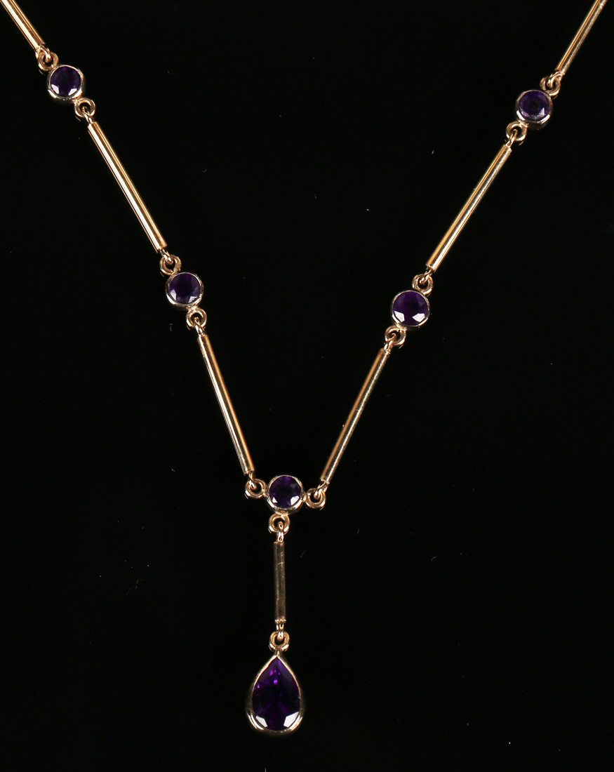 A 9ct gold and amethyst necklace, the front with a pear shaped amethyst drop, otherwise in a bar