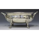 A George III silver sauce tureen of oval form with gadrooned rim flanked by foliate loop handles,