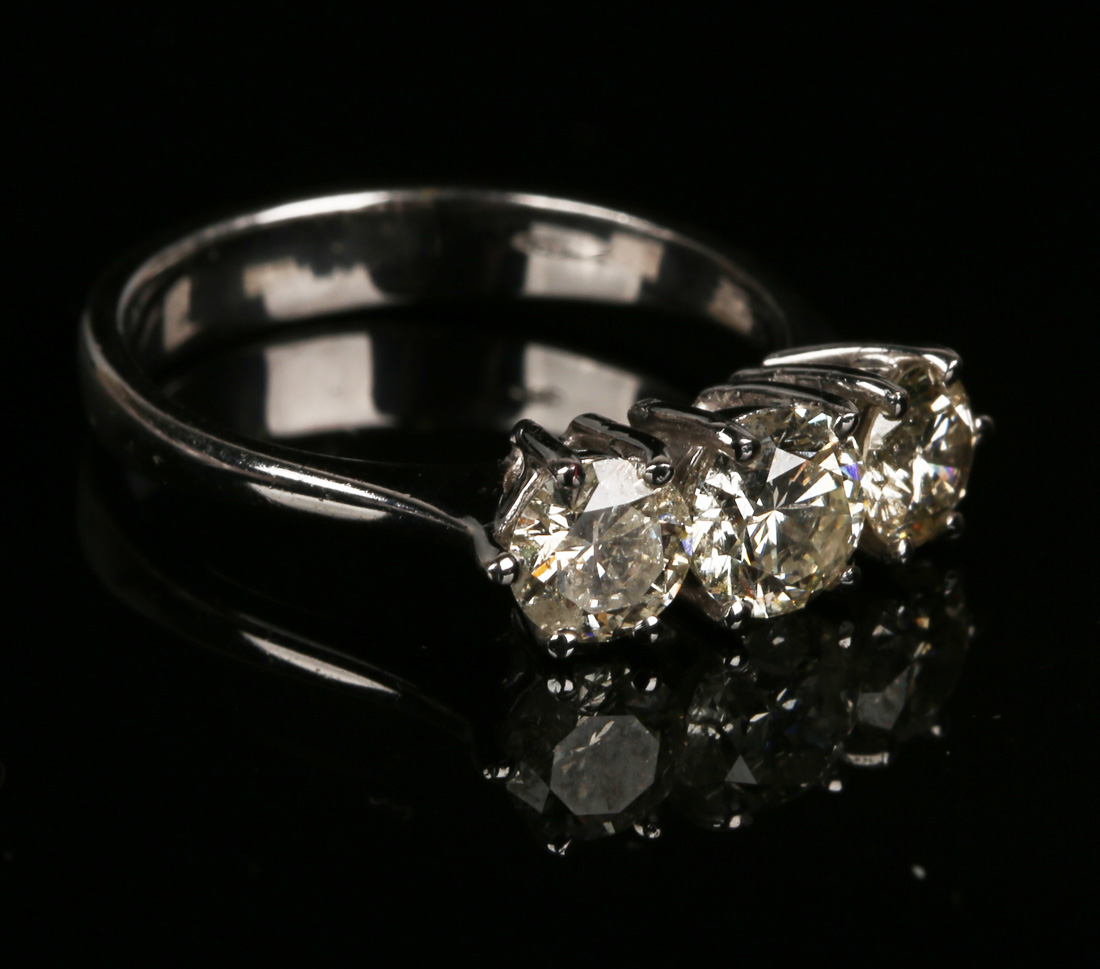 An 18ct white gold and diamond ring, claw set with three circular cut diamonds graduating in size to