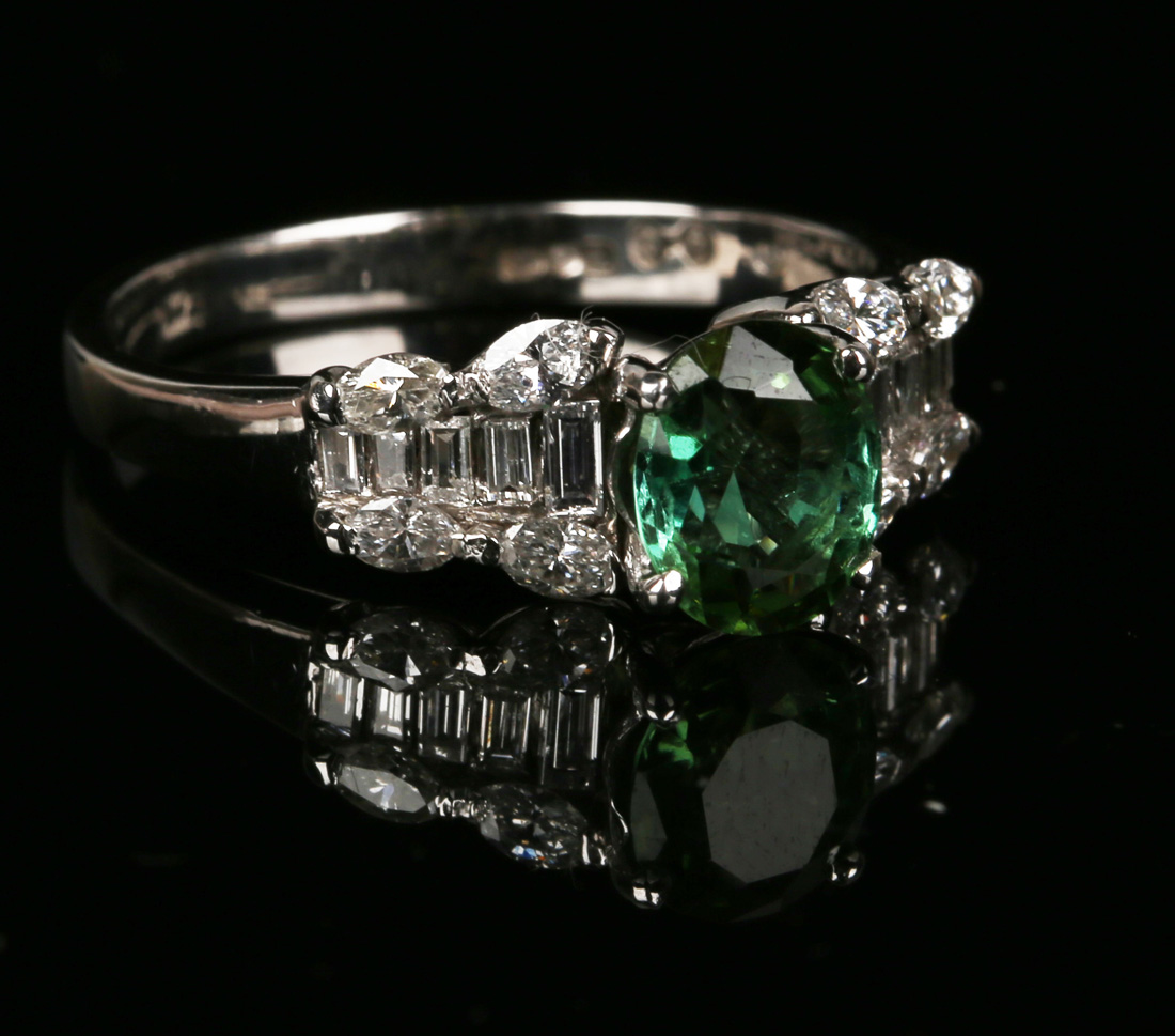 An 18ct white gold, green tourmaline and diamond set ring, claw set with an oval cut green