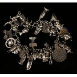 A silver curblink charm bracelet, fitted with a variety of mostly silver charms, including a gypsy