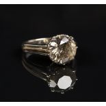 A two colour gold and champagne coloured diamond single stone ring, claw set with a circular cut