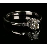 A white gold and diamond ring, claw set with an oval cut diamond between baguette diamond single