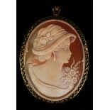 A gold mounted oval shell cameo pendant brooch, carved as the portrait of a lady wearing a bonnet