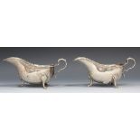 A pair of George V silver sauce boats, each with a cast scroll rim and foliate capped scroll handle,