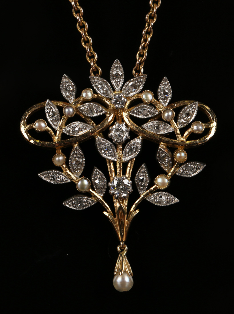 A two colour gold, diamond and cultured pearl pendant of scrolling stem form with foliate detail,
