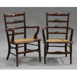 A pair of late 19th century fruitwood ladder back armchairs with caned seats, on turned tapering