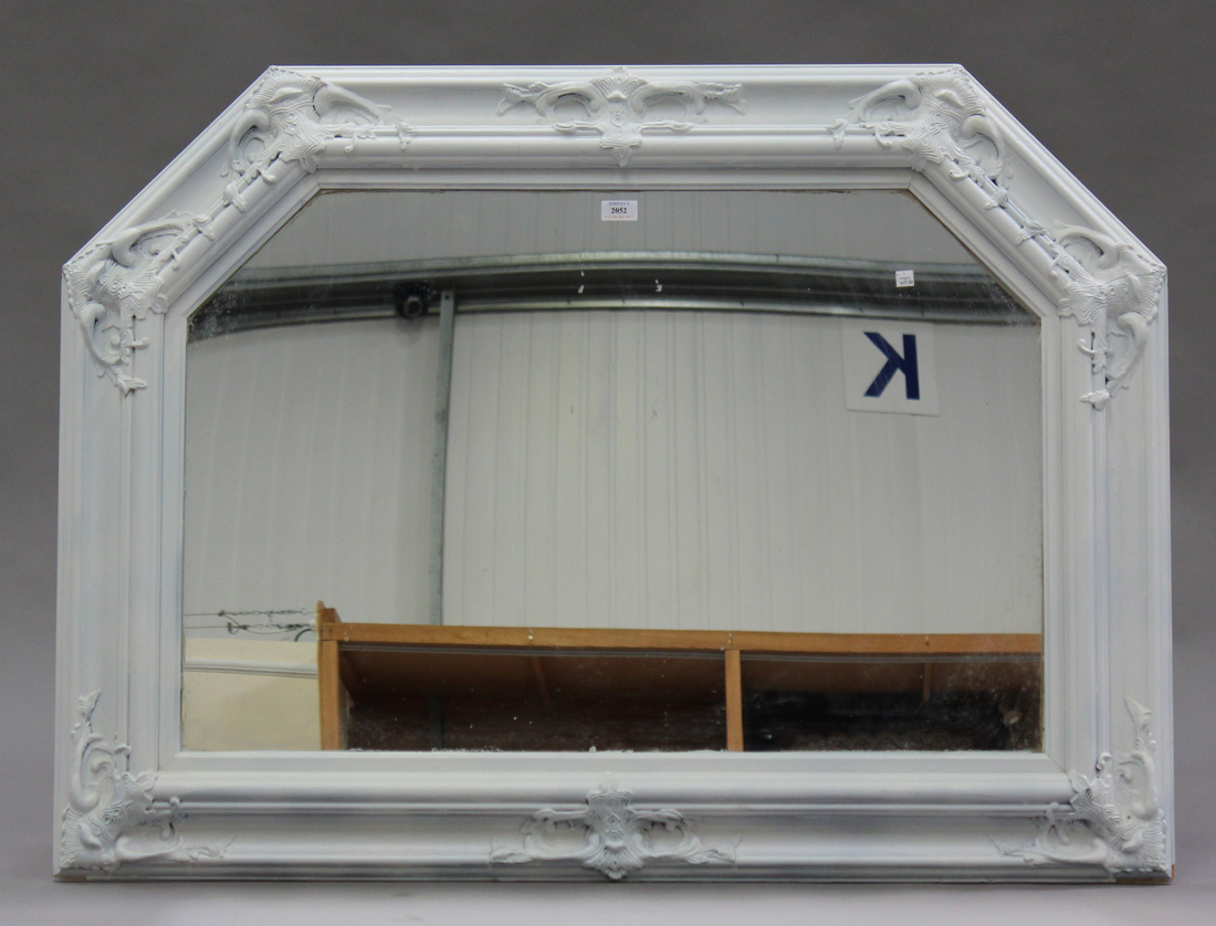 A modern white painted overmantel wall mirror with moulded leaf scroll decoration, 87cm x 114cm.