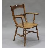 An early 20th century beech and elm bar back armchair with solid seat, raised on turned legs