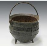 A cast iron cooking pot, 18th/19th century, with overhead swing handle and squat tripod feet, height