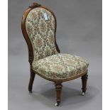 A Victorian walnut nursing chair with carved decoration, the upholstered seat and back raised on