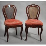 A pair of mid-19th century French mahogany side chairs with caned seats and backs, raised on