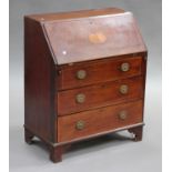 An Edwardian mahogany bureau with inlaid decoration, the fall front above three drawers, raised on