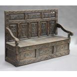 A late 19th century oak box seat settle, the panelled back carved with full-length figures of a king