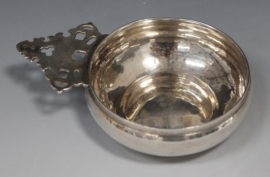 A silver tasse du vin of circular form with pierced tab handle, London 1938 by Tessiers Ltd,