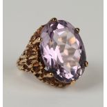 A 9ct gold ring, mounted with an oval cut amethyst in a raised abstract design, London 1971, ring