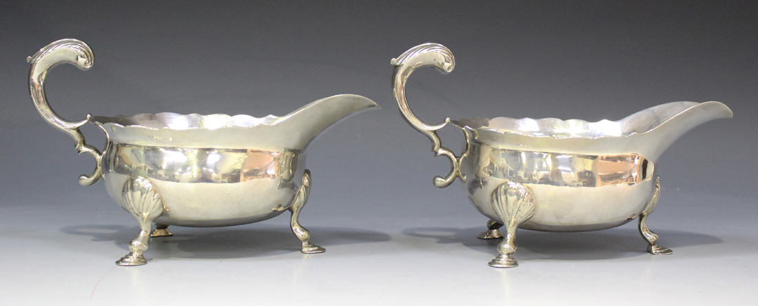 A pair of George II silver sauce boats, each with foliate capped flying scroll handle, on scallop