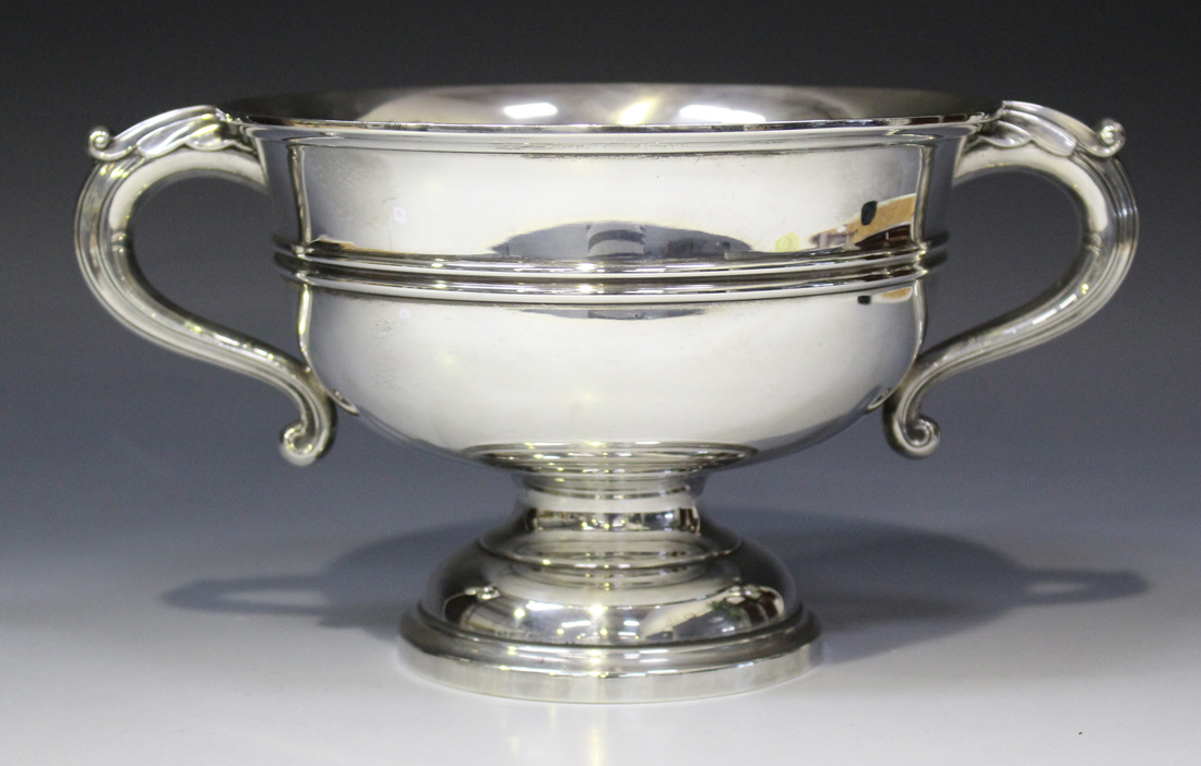 A George V silver two handled trophy cup, the circular body flanked by a pair of foliate capped