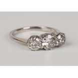 An 18ct white gold and diamond three stone ring, claw set with circular cut diamonds, ring size