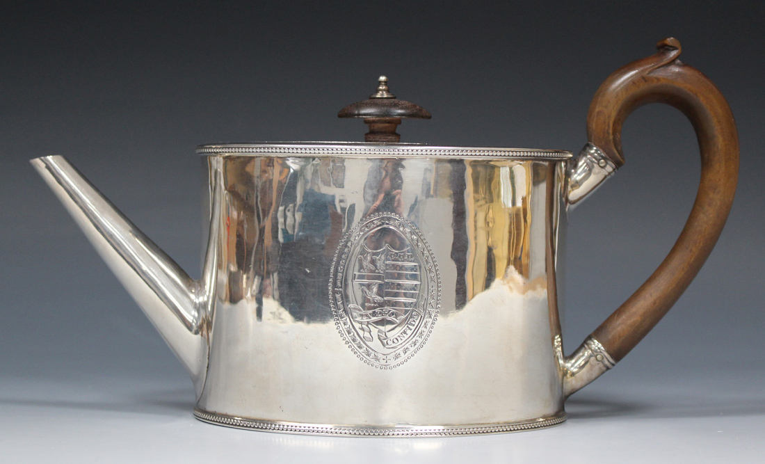 A George III silver oval teapot, engraved with an oval cartouche and shield shaped crest, the banner