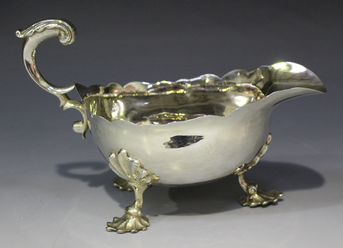 A George IV silver sauce boat with shaped rim and foliate capped flying scroll handle, raised on