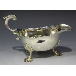 A George IV silver sauce boat with shaped rim and foliate capped flying scroll handle, raised on