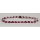 An 18ct white gold, treated ruby and diamond bracelet, claw set with a row of oval cut rubies