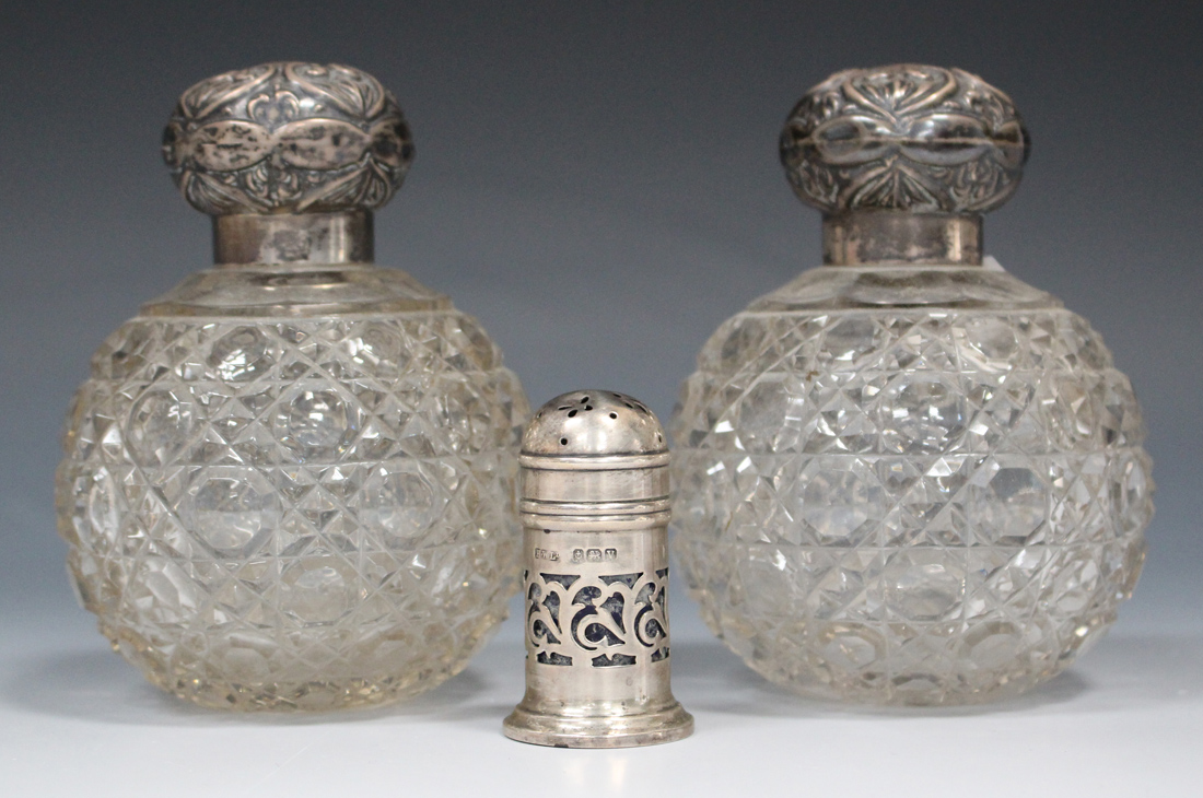 A pair of George V silver topped cut glass globular scent bottle, each screw top with embossed