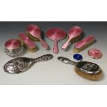 A George V silver and pink enamel six piece dressing table set, comprising two hairbrushes,