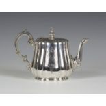 A Victorian silver teapot of shaped circular form, engraved with foliate scroll borders and opposing