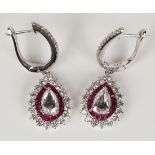 A pair of white gold, ruby and diamond pendant earrings, each claw set with a principal pear