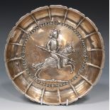 A Continental silver circular dish with pinched rim, the centre decorated in relief with a
