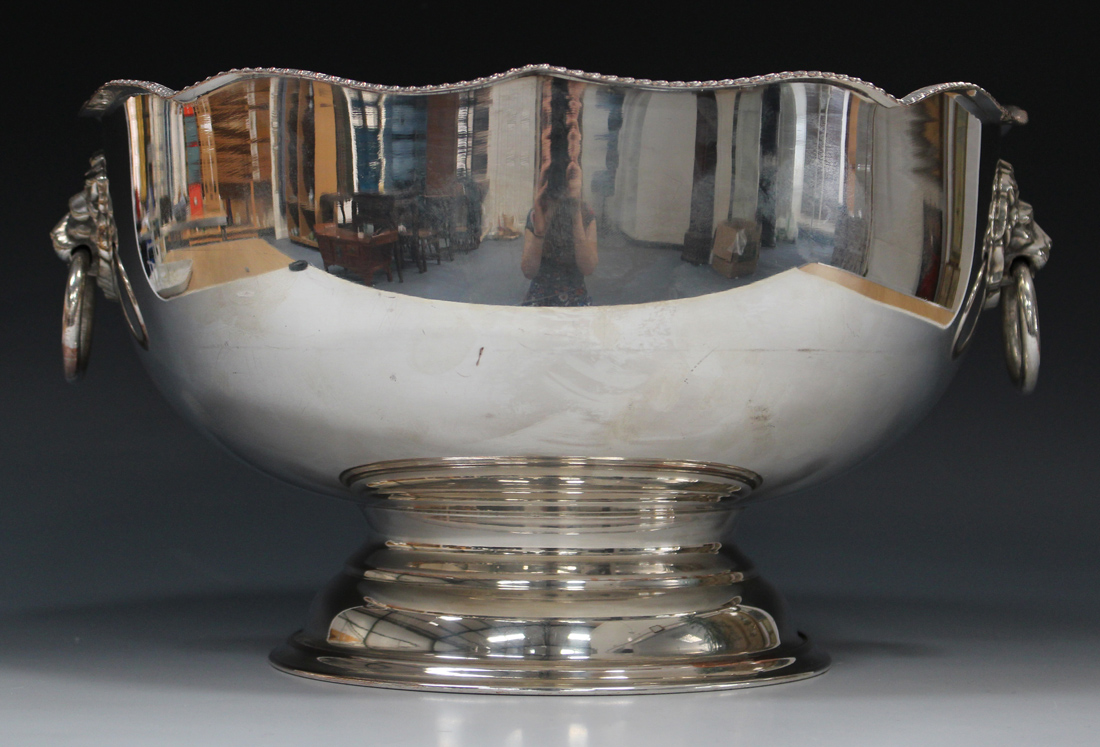 A 20th century plated punch bowl with serpentine shaped rim, flanked by two lion mask ring