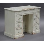 A 20th century white painted pine kneehole desk, fitted with seven drawers and a cupboard, on a