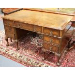 A 20th century Queen Anne style walnut twin pedestal desk, fitted with seven drawers, on carved