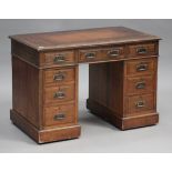 An Edwardian oak twin pedestal desk, fitted with an arrangement of nine drawers, on plinth bases,