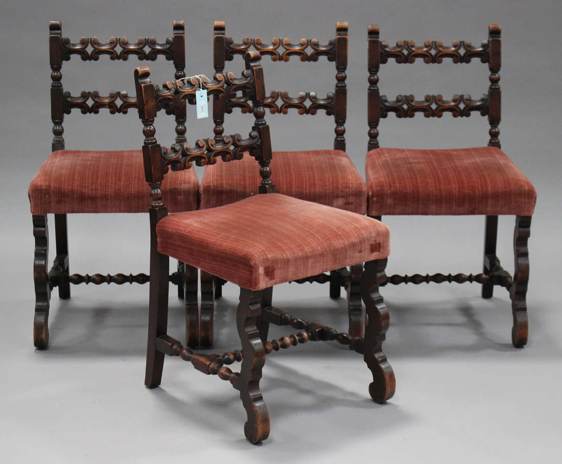 A set of four early 20th century carved oak bar back chairs, the overstuffed seats on shaped legs,