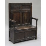 An 18th century and later panelled oak box seat settle with carved decoration, on stile supports,