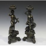 A pair of modern dark brown patinated cast bronze figural candlesticks, each putto and dolphin