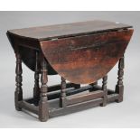 A late 18th century oak oval gateleg dining table, on turned and block legs united by stretchers,