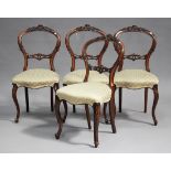 A set of four Victorian walnut spoon back dining chairs with carved decoration, the overstuffed
