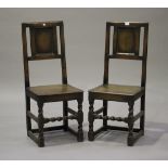 A pair of 17th century style oak panelled back side chairs with solid seats, raised on barley