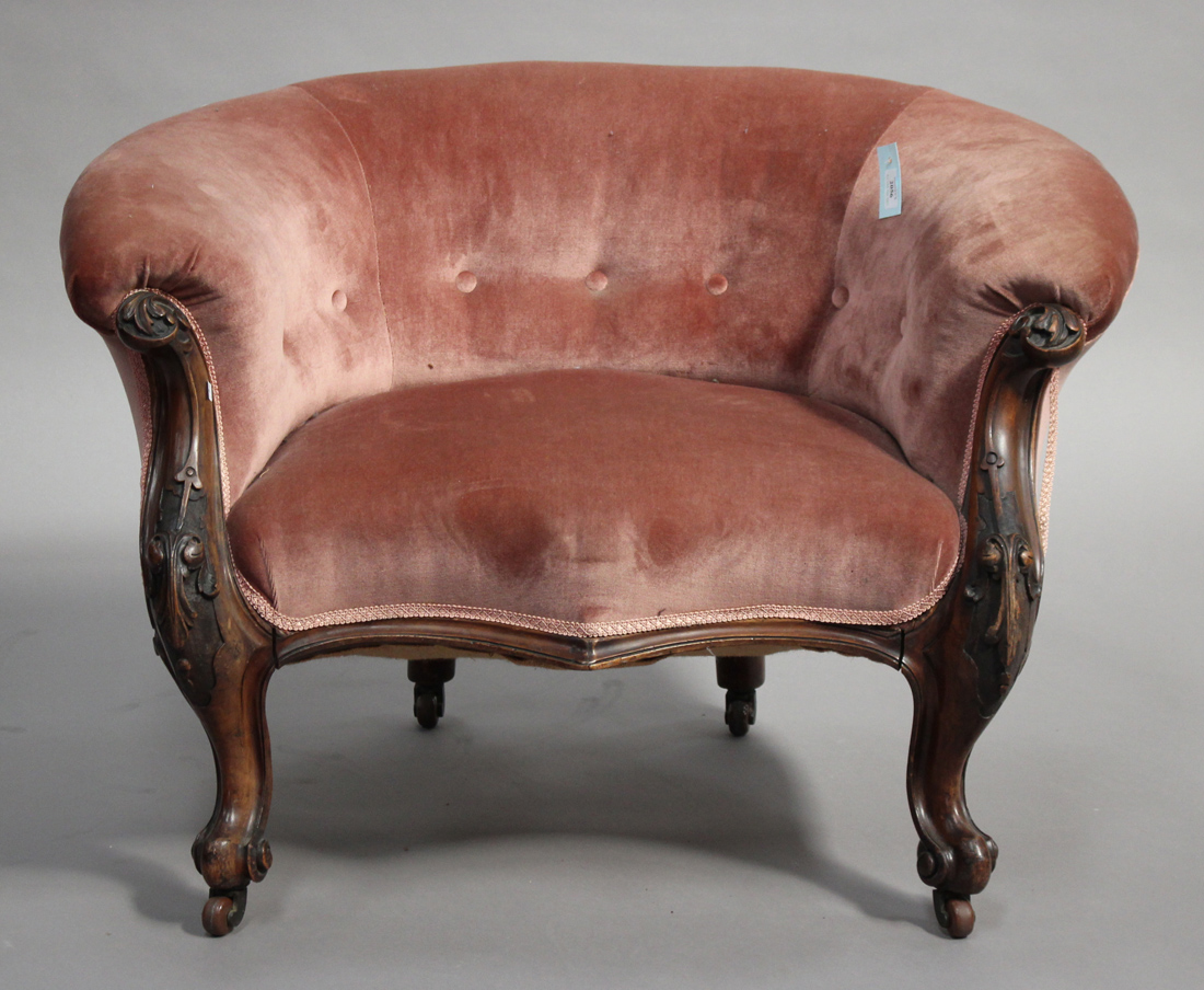 A Victorian walnut low-backed salon armchair, upholstered in pink velour, on carved cabriole legs,