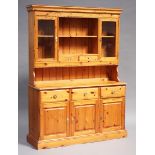 A late 20th century pine kitchen dresser, the shelf back above drawers and cupboards, on a plinth