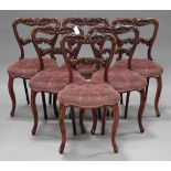 A set of six early Victorian rosewood dining chairs with carved foliate backs, the overstuffed seats