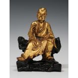 A Chinese carved giltwood figure of a monk, late Qing dynasty, modelled seated holding a scroll