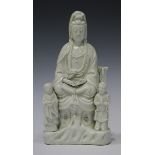 A Chinese blanc-de-Chine porcelain figure group, Kangxi period, modelled as a seated Guanyin flanked