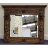 A late Victorian oak wall mirror, the frame carved with masks and scrolling decoration, 96cm x