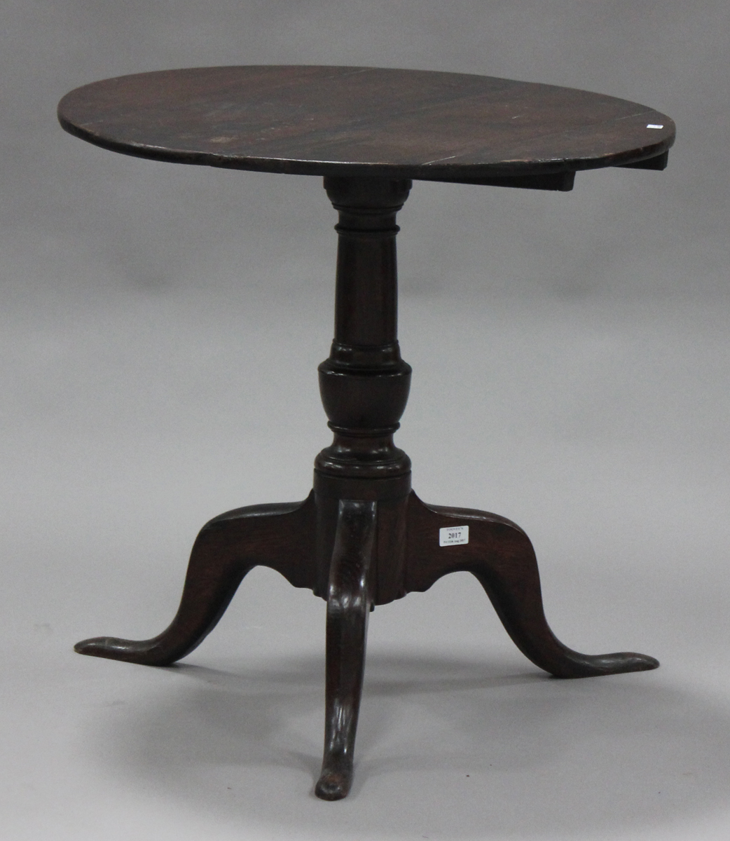 An 18th century oak tip-top wine table, the circular top raised on a turned column and tripod